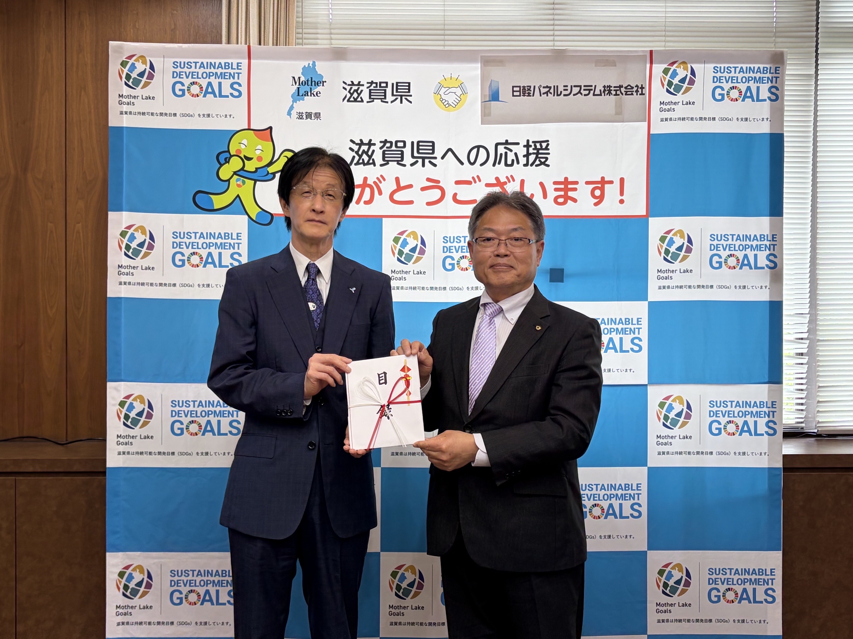 当社の室伏徳康常務取締役から滋賀県の東勝副知事へ寄附目録が手渡されました